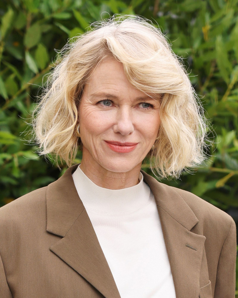 Naomi Watts wearing a brown blazer and cream mock neck shirt
